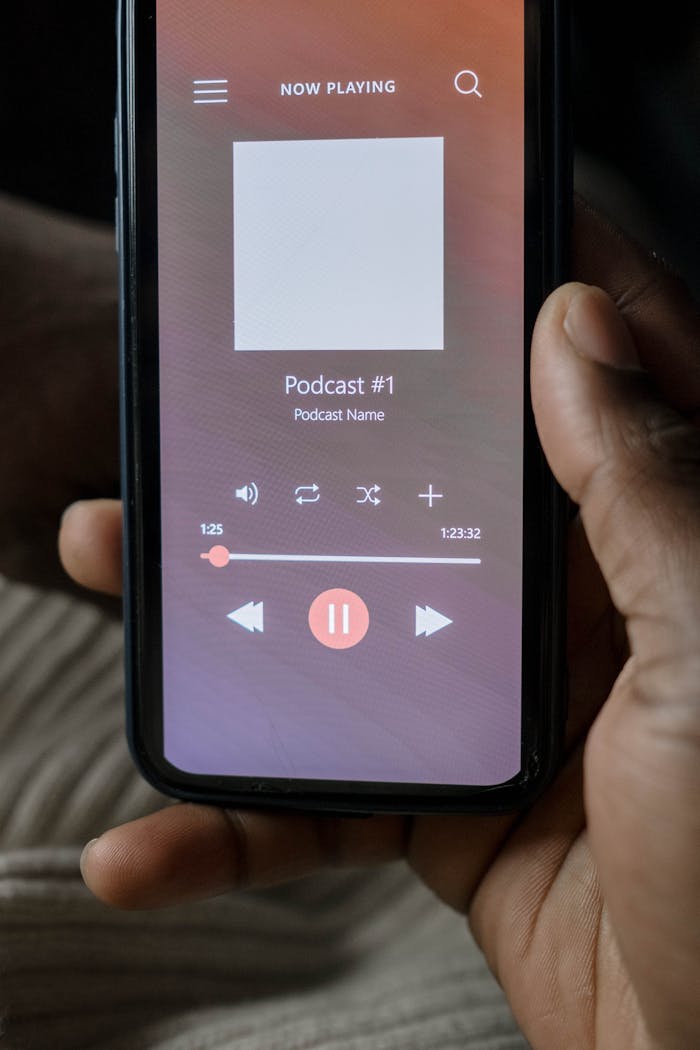 Close-up of a hand holding a smartphone playing a podcast.